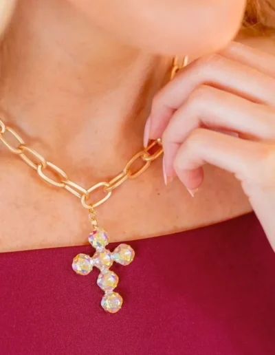 Woman wearing gold chain with cross pendant.