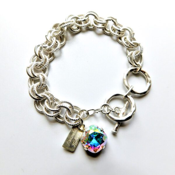 A silver bracelet with a large chain and a small charm.