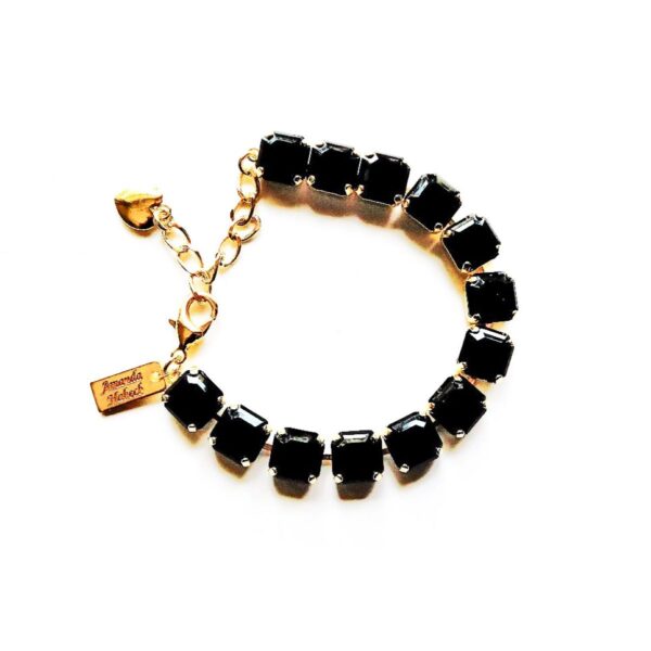 A black bracelet with gold chain and charms.