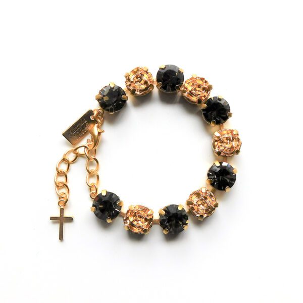 A gold cross and black beads bracelet on white background