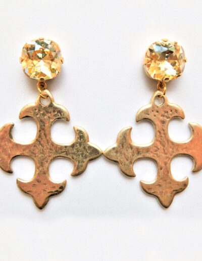 A pair of gold earrings with a cross on top.