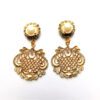 A pair of gold earrings with a large filigree design.