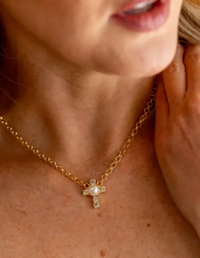 Woman wearing gold cross necklace, close-up.
