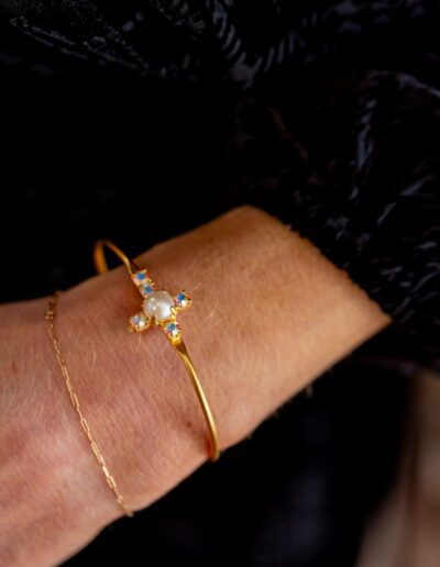 Gold bracelet with gemstone details on wrist.